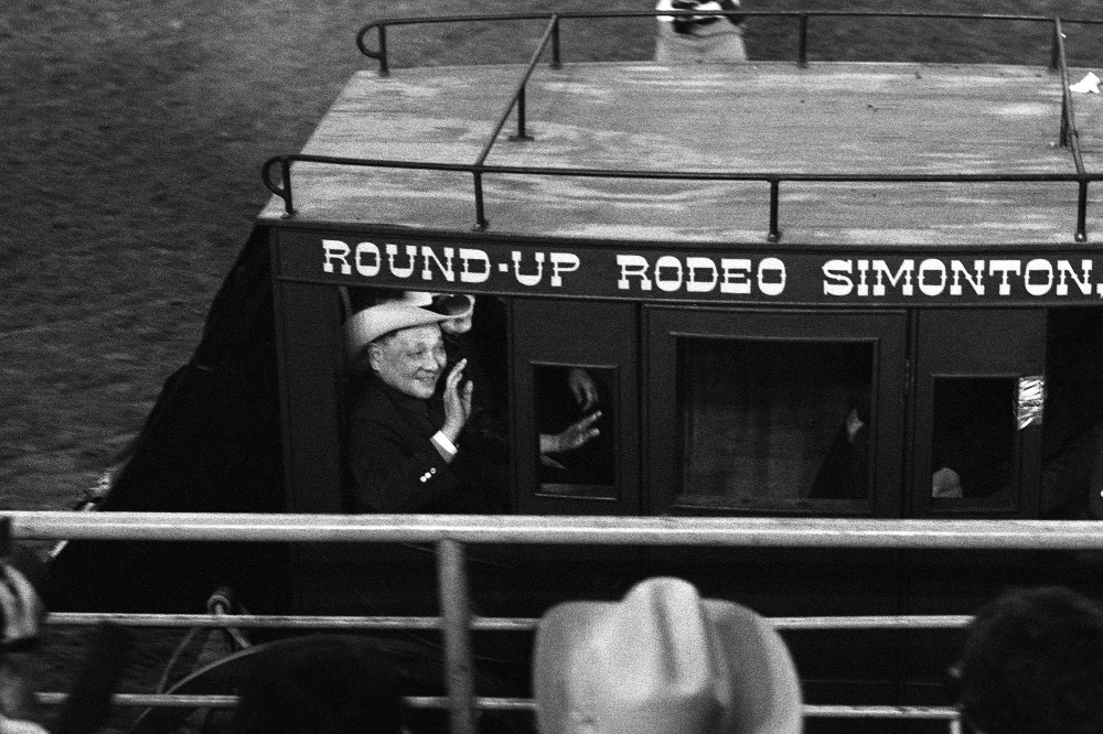 頭戴牛仔帽的鄧小平坐在馬車與觀眾招手，全場氣氛高漲，高聲呼喚。