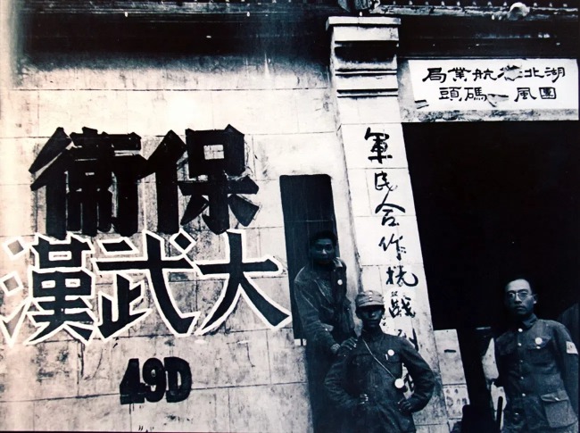 武汉经济商业基础好，又是南北铁路和长江水路交汇，当时还有国民政府西迁机构和物资滞留，当局动员110万兵力防守。图为当地码头的“保卫大武汉”标语。