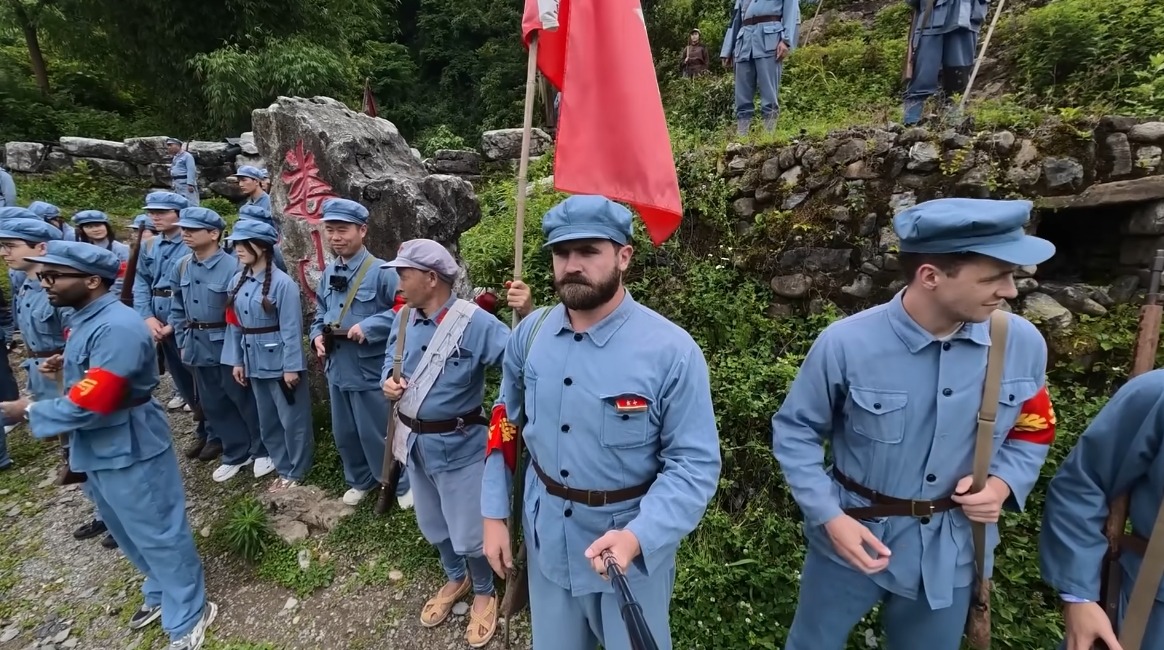 英國博主Mike Okay身穿紅軍制服、手持自拍杆，在貴州遵義婁山關與其他參與者體驗「跟着團長攻打婁山關」沉浸式活動。