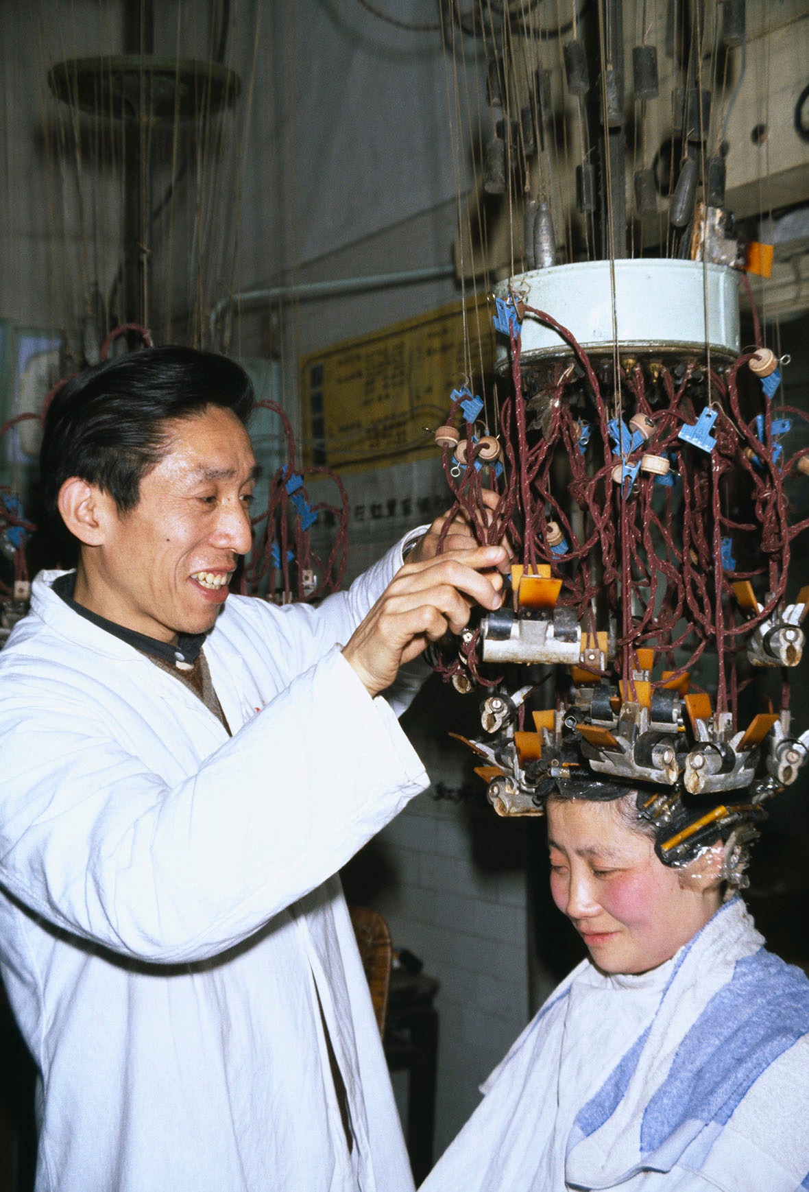 1979年中國，笑容可掬的髮型師在顧客頭上夾滿燙髮夾。