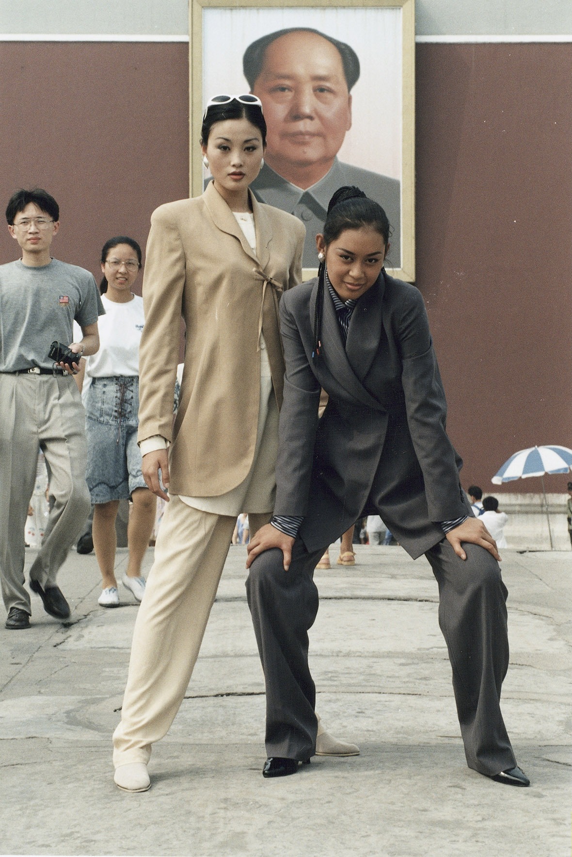 兩名模特兒穿上米色和灰色的休閒西褲套裝，在毛澤東的畫像前擺甫士。