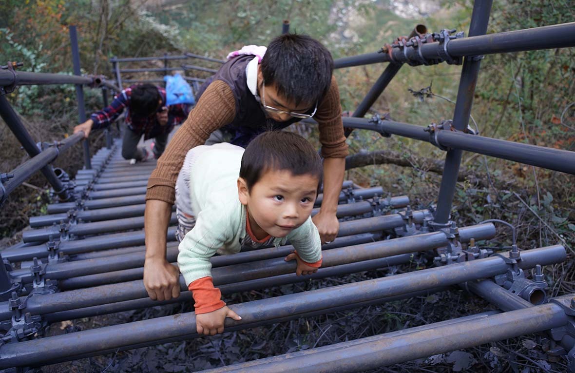 鋼梯建成後，勒爾小學的老師帶着3歲的兒子跟着學生爬梯上懸崖村家訪。過去路不好走，他從未帶過兒子上山。