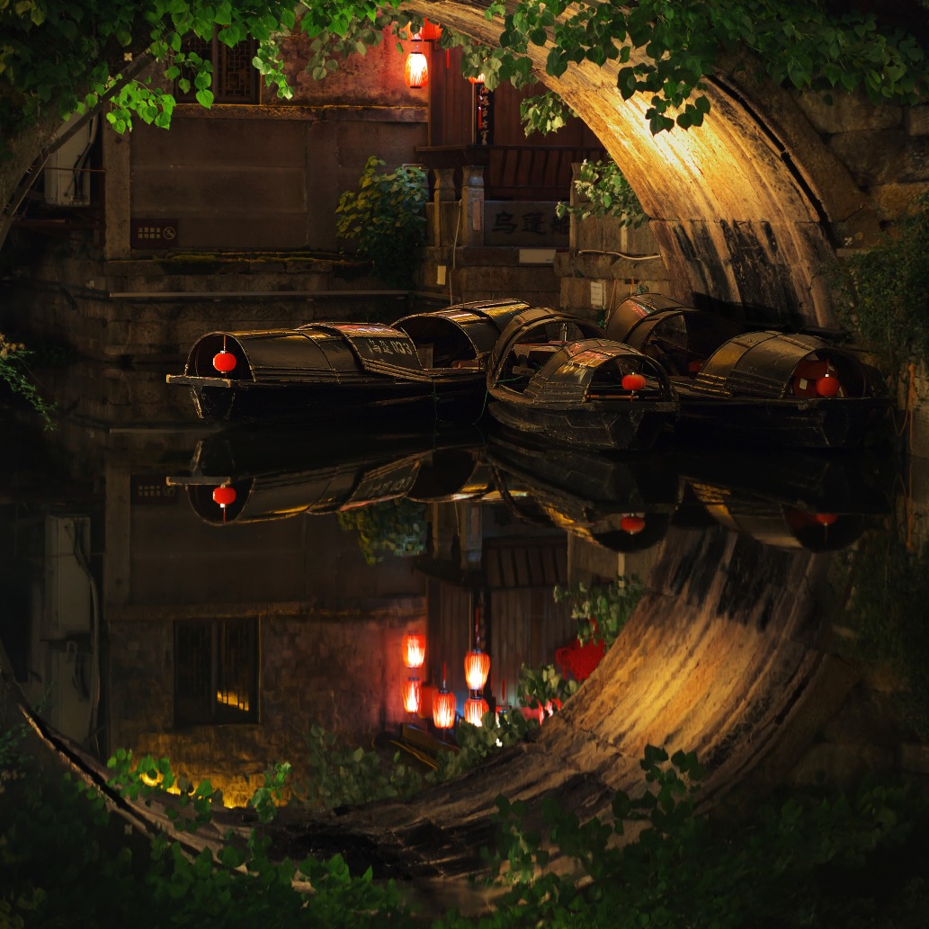 Below this single-arch stone bridge, the awning boat and red lanterns depict a charming water town.