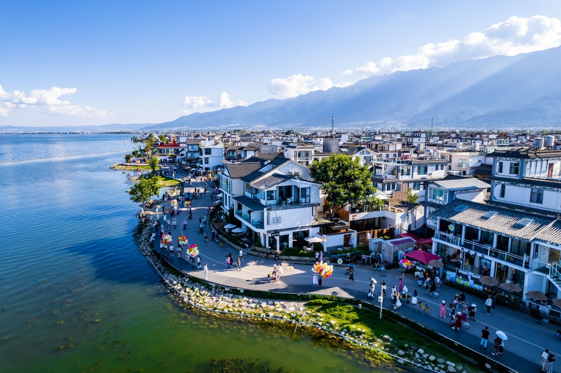 大理洱海航拍景色，遊客在洱海邊散步慢遊，展現雲南旅居的生活場景。