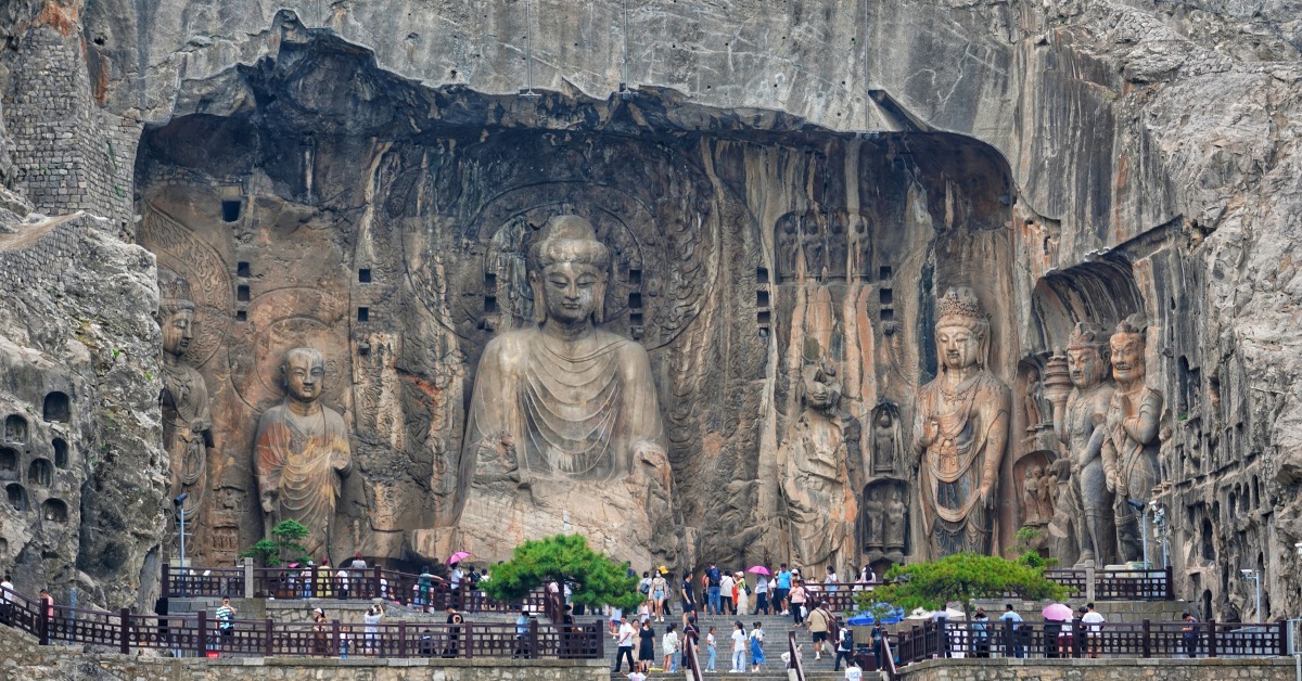 河南洛陽龍門石窟萬佛雕像與遊客人潮，展現中原千年佛教石刻藝術與文化旅遊人氣。