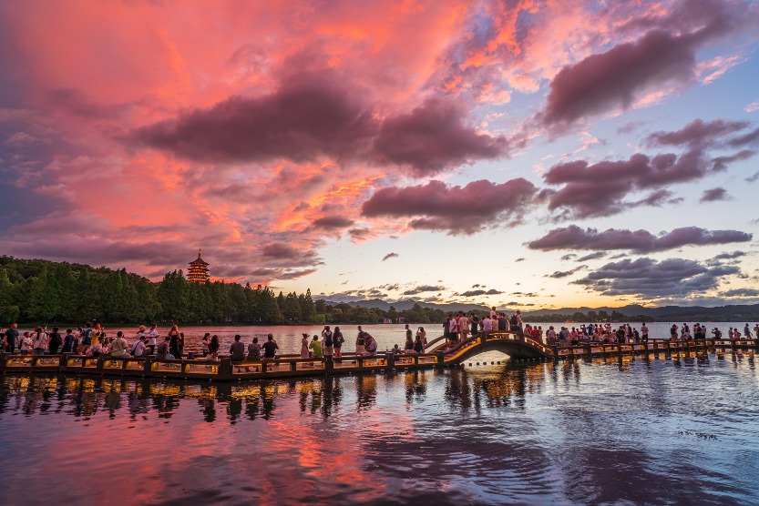 杭州西湖晚霞迷人，遠處的雷峰塔亮燈，吸引遊客駐足拍照。