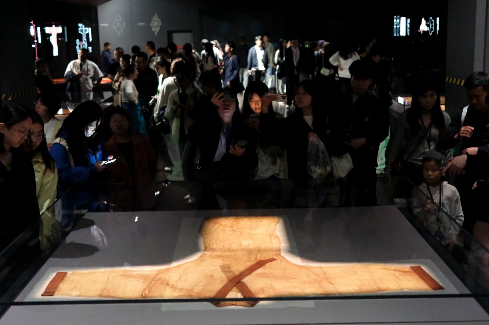 湖南省博物館「長沙馬王堆漢墓陳列」展廳，大批觀眾圍觀玻璃展櫃內的素紗單衣，遊人舉手拍照記錄珍貴漢代文物
