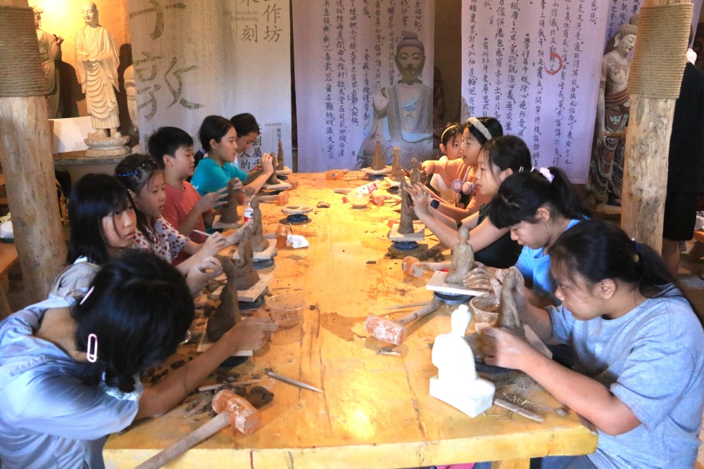 2023年7月26日，甘肃酒泉，在敦煌市莫高里工匠村研学课堂，孩子们学习制作木胎泥塑。