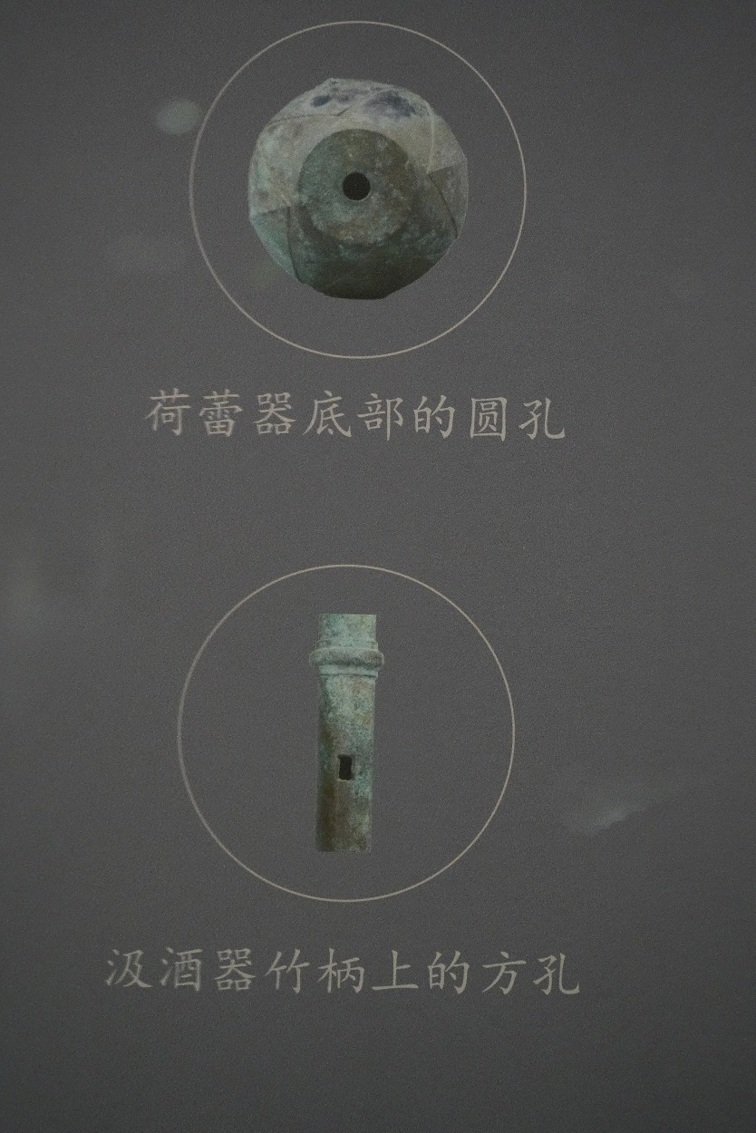 汲酒器上有兩個孔，一個是在荷蕾球狀器底部的圓孔，另一個是在竹節長柄上的方孔。
