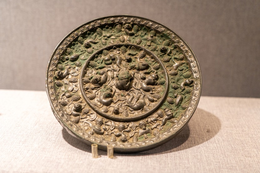 河南洛陽博物館藏唐代海獸葡萄紋鏡，鏡背布滿瑞獸、葡萄藤蔓和果串的高浮雕紋飾。