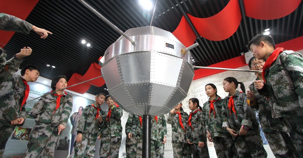 The picture shows students from the Chinese Mainland visiting a model of Dongfanghong-1