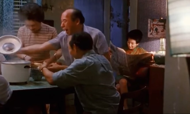 王家衛的電影《花樣年華》中，張曼玉飾演的蘇麗珍坐在一旁看報紙，鄰居們則雀躍地試用她丈夫從日本帶回來的電飯煲。（網上截圖）