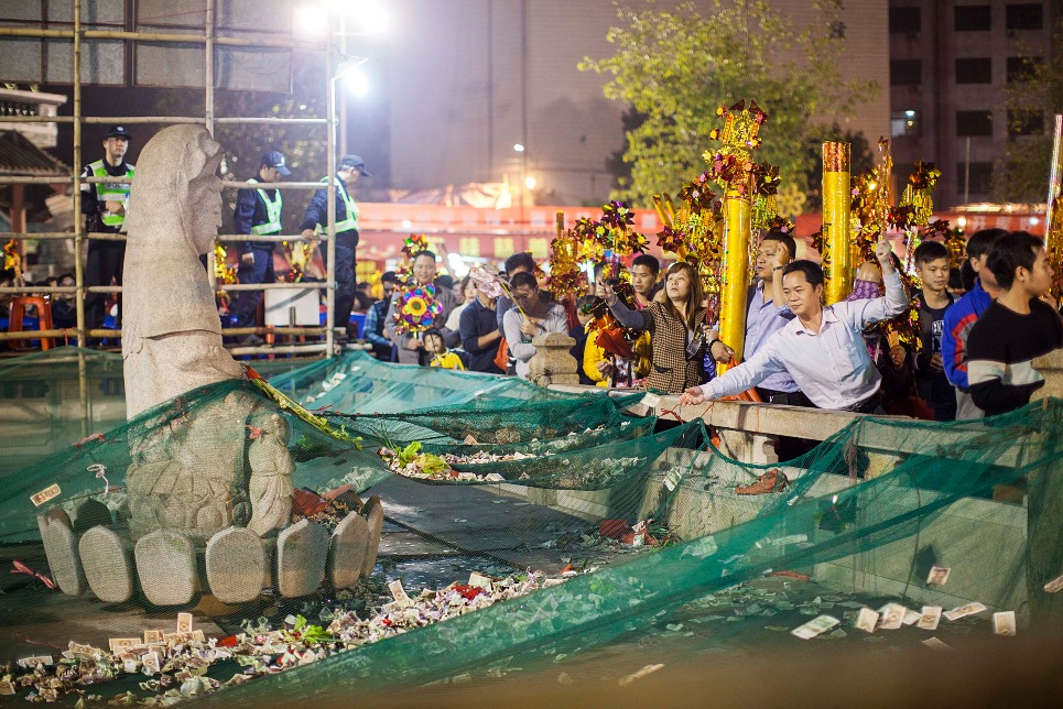 在廣東順德容桂白蓮公園，市民手持風車在觀音像前投擲硬幣並輕聲許願借庫。圖片攝於2015年。（圖片來源：人民視覺）