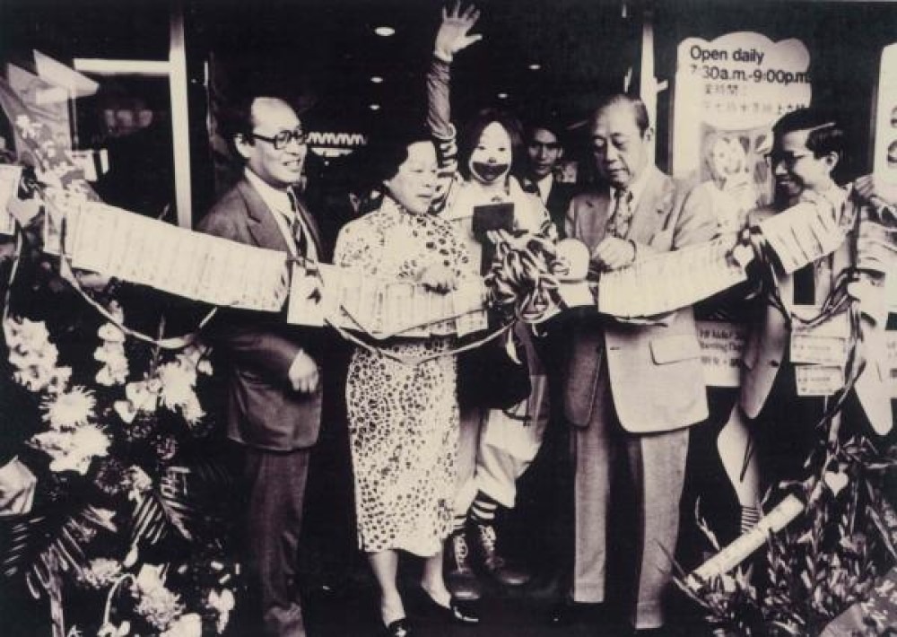 1975年1月26日，麥當勞於在銅鑼灣百德新街開設本港第一間麥當勞。根據當年報章介紹，餐廳面積達3,000多呎，設有60個座位。圖為「香港麥當勞之父」伍日照（左一）與華人富商馮秉芬（右二），在麥當勞叔叔陪同下為餐廳剪綵。（網上圖片）