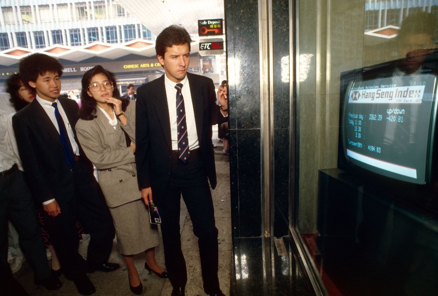 1987年股災的黑色星期一，市民在中環一家銀行門口專注觀看屏幕上的財經資訊。（圖片來源：Getty）