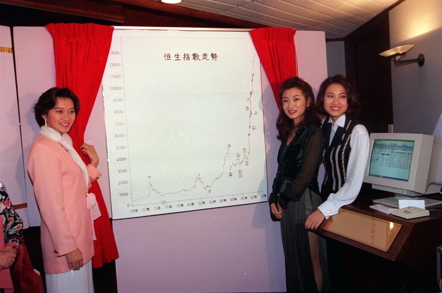 圖片攝於1993年，當年的應屆三甲香港小姐（左起）季軍余少寶、冠軍莫可欣及亞軍林麗薇，為一個財經節目介紹恒生指數走勢圖表。（圖片來源：Getty）
