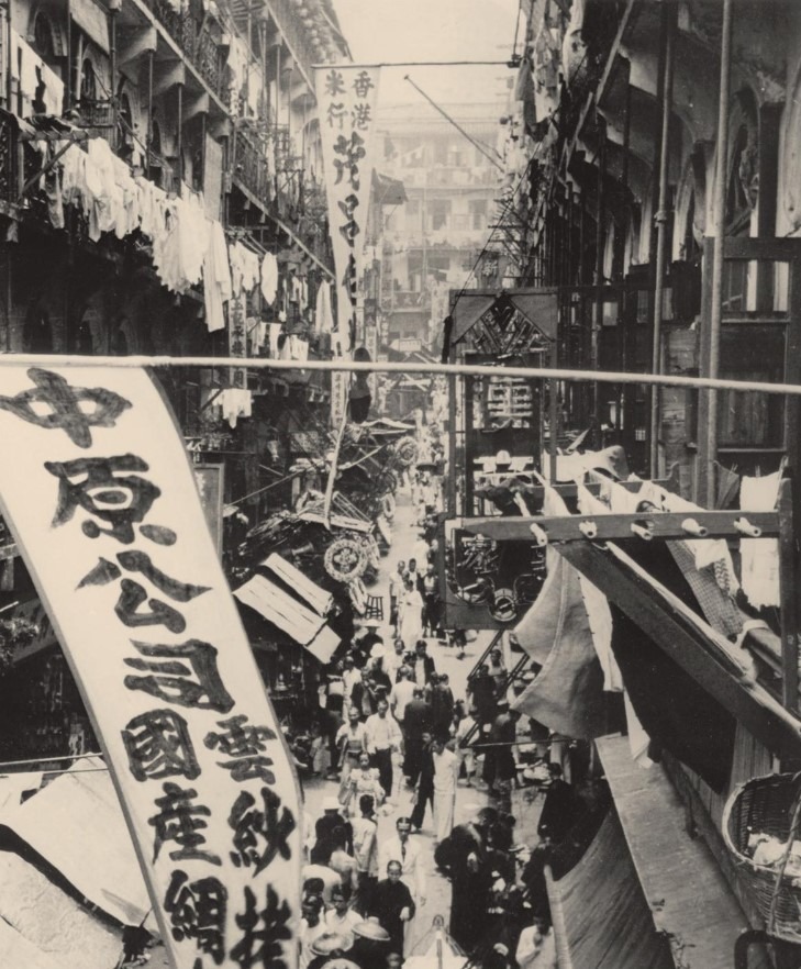 圖為1950年代由皇后大道西望向水坑口街的情況，當時街道狹窄，尚未可以行駛汽車，兩旁擠滿小販。（圖片來源：《香港百年飲食場所》／香港歷史博物館藏品）