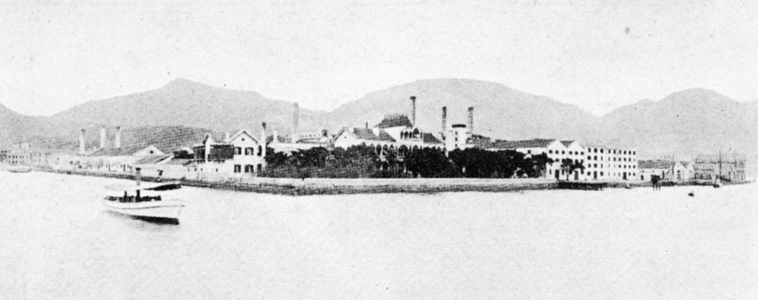 怡和洋行1878年在糖街一帶開立了香港第一間煉糖廠「中華火車糖局（China Sugar Refinery）」，簡稱中華糖局，從遠處望見糖廠的大煙囪。（圖片來源：香港記憶／香港大學圖書館）