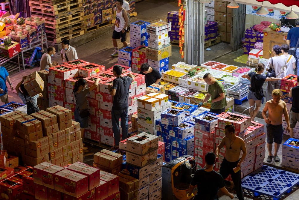 油麻地果栏的工人正在忙碌地搬运水果，而栏商就会盘点暂时存放在街上的货量。