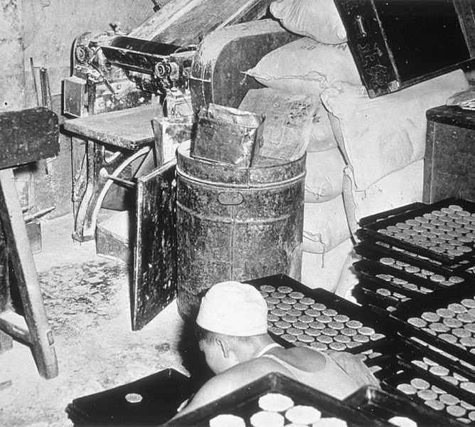 早期奇华饼家的伙计以床板做案台、大铁罐为烘炉做饼的情况。