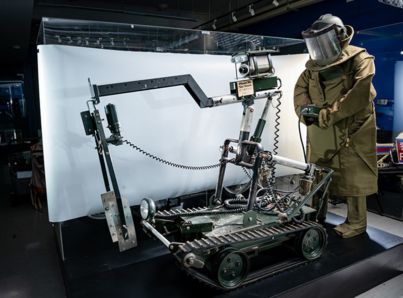 图中是旧式拆弹车型号 独轮车马克7号”，是以机械臂夹起爆炸品，转移到适合位置引爆。