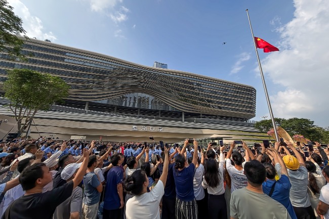 新皇崗口岸2026年10月12日啟用，啟用儀式上人們舉起手機拍攝升起的中國國旗。 