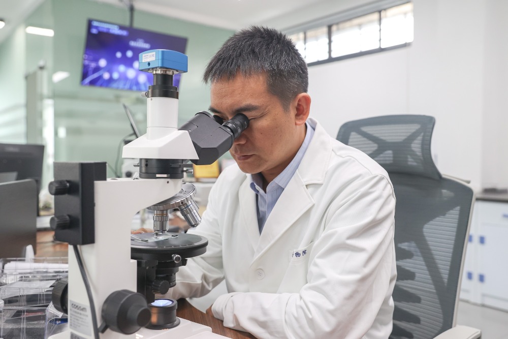 景德鎮古陶瓷基因庫實驗室內，御窯博物院院長翁彥俊正使用電子顯微鏡觀察古瓷片標本。