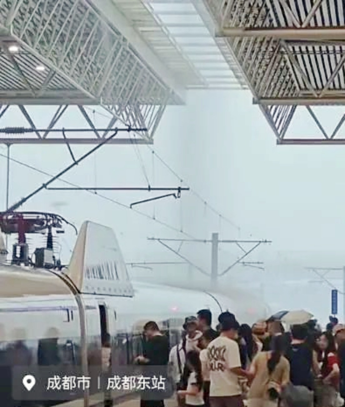 成都暴雨，高鐵站雖有頂棚，但雨水仍被風吹到站台上，有候車旅客打傘擋雨。
