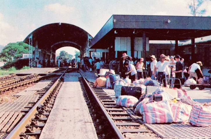 80年代羅湖火車站，頭戴草帽、身穿白汗衣的旅客以大包小包的紅白藍袋盛載物品回鄉。
