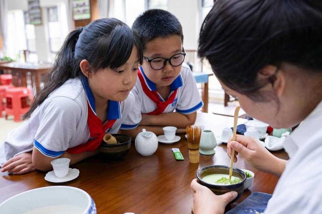 Students participating in study tours in the tea room of Guizhou Tea Industry Park, Jiangkou County, Guizhou Province, observing matcha beverage preparation
