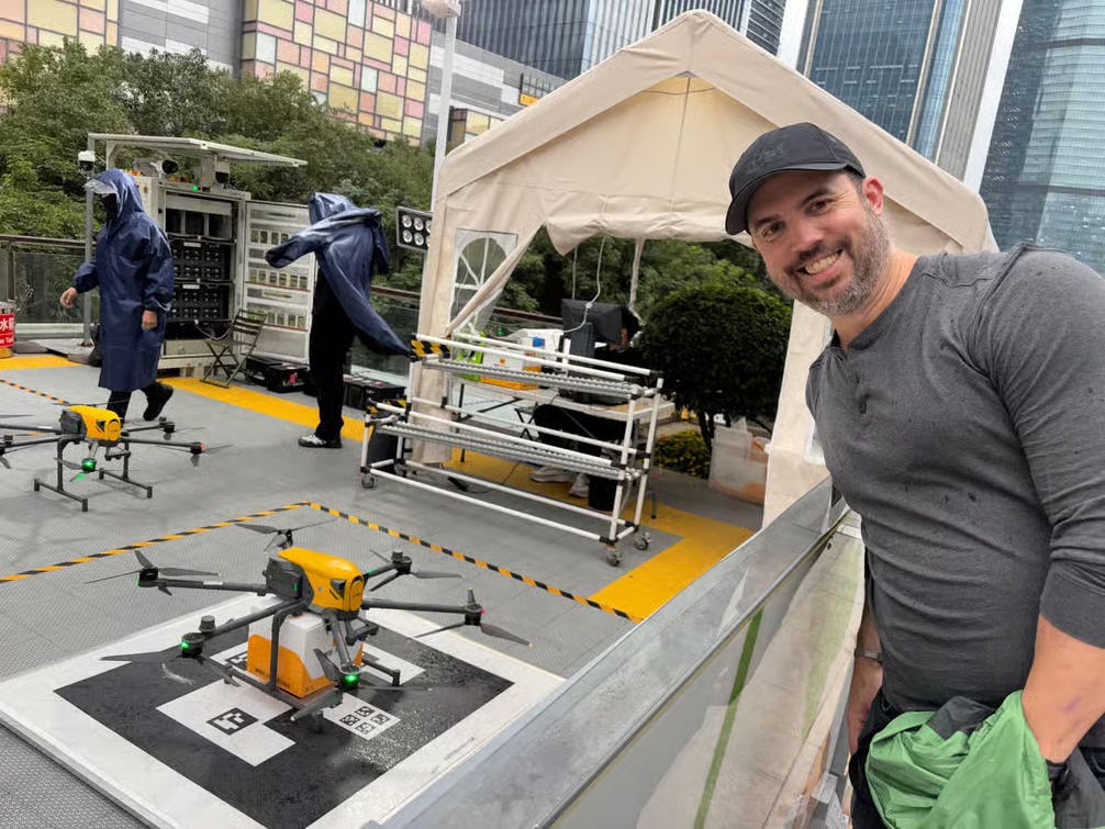 In a drone delivery area in Shenzhen, a foreign tourist excitedly poses for a photo with a drone food delivery.