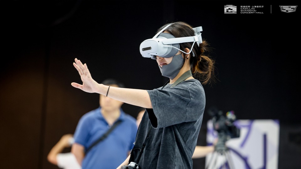 上海音樂廳內，一名觀眾戴上VR頭戴式裝置並伸手互動。