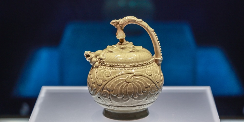 陝西歷史博物館的文物，五代青瓷提梁倒灌壺，瓷壺有伏鳳式提梁，以花蒂象徵壺蓋，蓋、壺銜接處堆塑哺乳母子獅，球形壺腹刻飾纏枝牡丹，造型奇巧，是耀窯瓷器出類拔萃的珍品。