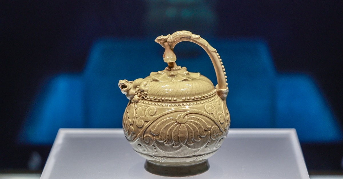 陝西歷史博物館的文物，五代青瓷提梁倒灌壺，瓷壺有伏鳳式提梁，以花蒂象徵壺蓋，蓋、壺銜接處堆塑哺乳母子獅，球形壺腹刻飾纏枝牡丹，造型奇巧，是耀窯瓷器出類拔萃的珍品。