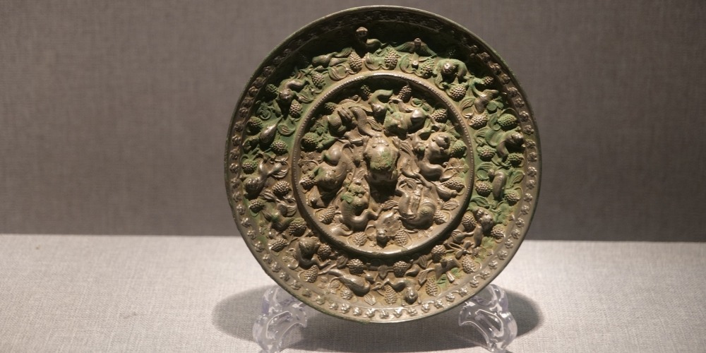 河南洛陽博物館藏唐代海獸葡萄紋銅鏡，鏡背飾瑞獸、葡萄藤蔓、果串及禽鳥紋樣。