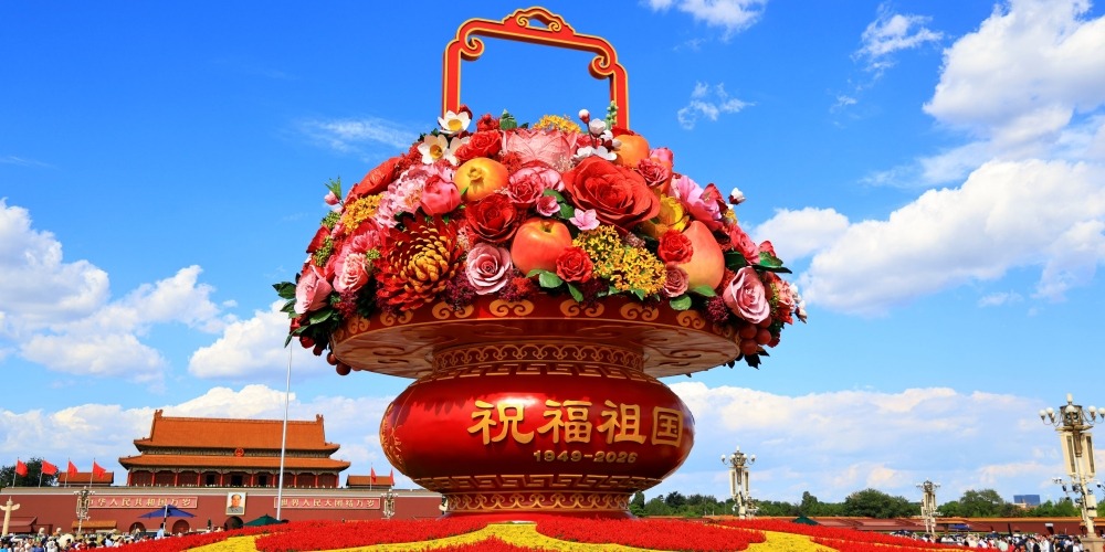 天安門廣場「祝福祖國」巨型花果籃全景，籃身寫有「祝福祖國，1949-2026」，前景為國慶花壇，背景可見天安門城樓與藍天白雲。